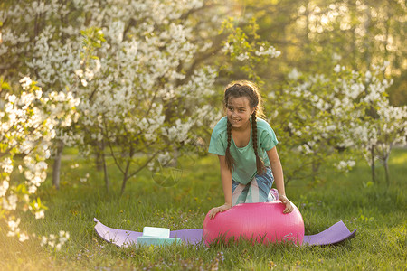 优秀是一种习惯一个小女孩做瑜伽 躺在公园体育垫子上 健康的生活方式是一种幼稚习惯 笑声运动夫妻童年冥想草地生活活力后院训练喜悦背景