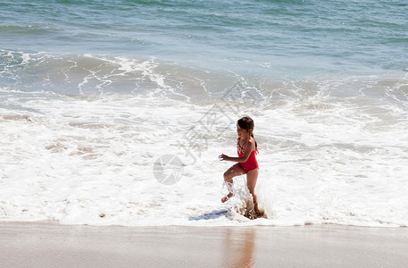 小女孩在海滩的冲浪中奔跑 快乐的 女性 健康 泳装红色的高清图片素材