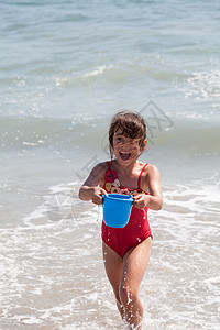 小女孩在海滩上跟一个酒桶玩耍 户外 湿的 海岸红色的高清图片素材