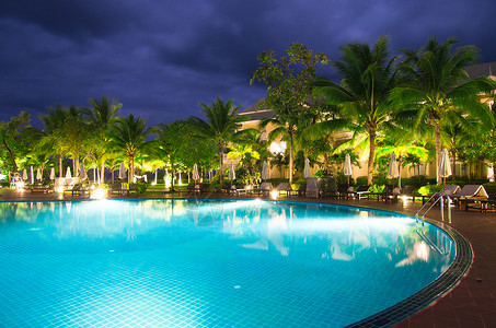 游泳池照明游泳池 树 发光的 现代的 椅子 椰子 假期 云 日落 户外的背景
