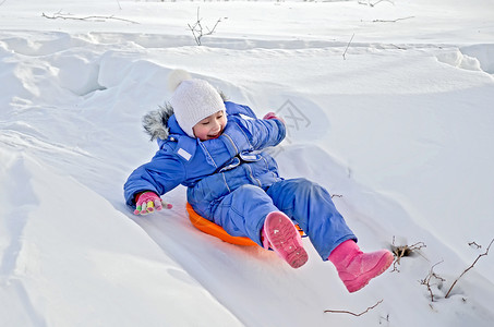 平底雪橇小女孩坐在雪地滑雪的雪橇上背景