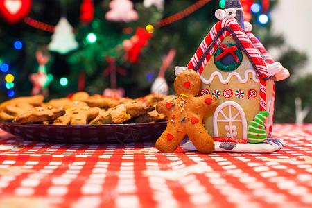 在圣诞树灯前的 糖果姜仁屋前 有一位可爱的姜饼男 姜饼曲奇 传统背景图片