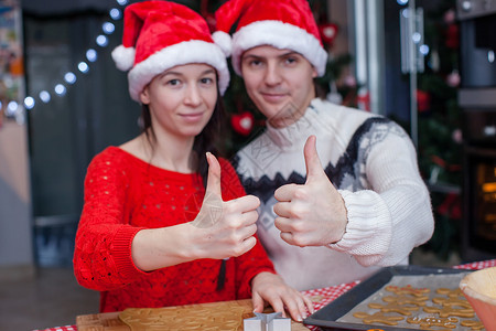 圣诞戴圣诞帽子的年轻快乐情侣在家里举起拇指高清图片