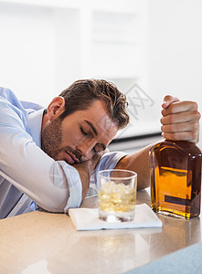 醉酒的商人抓住威士忌瓶睡着图片