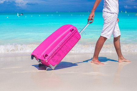 一个人在白色沙滩上拉行李高清图片