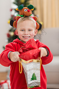 小男孩带着头巾怀着喜悦的小男孩在镜头前微笑 带着礼物 房子背景