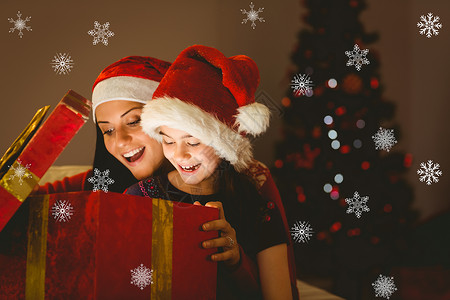 喜庆母亲和女儿的复合形象 开启了圣诞礼物 微笑 冰背景图片