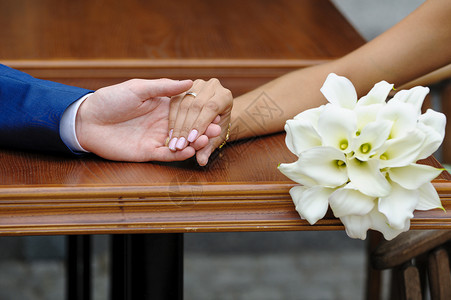 新娘握着新郎的手和婚礼花束快乐的高清图片素材