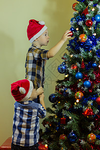 装饰圣诞树的小男孩们背景图片