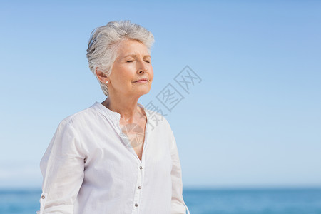 高级女子在沙滩上放松 海岸线 眼睛 女士 户外 波浪背景图片