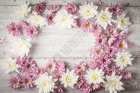 白木桌上白花和粉红花的边框背景图片