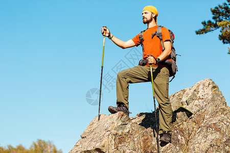 走还是留留着胡须的年轻男性正在穿越山区 旅游背包站在岩石山上 同时欣赏自然景观 在山区度过暑假 闲暇 远足背景