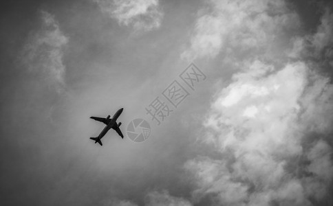 国际航空公司在乘坐灰色天空和白云起飞后出现的黑色和白色景象 高的背景