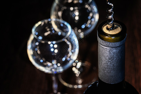 一瓶带开瓶器的葡萄酒 打开瓶子 玻璃 在桌子上 红酒杯背景图片