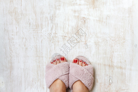 毛毛拖鞋双脚和红指甲 在家庭毛毛 毛毛的粉红色拖鞋上 鞋类 凉鞋背景