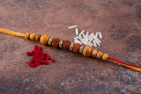 摩拉基大圆石Rakhi带稻谷 石本底有Kumkum 印度传统手腕乐队 是兄弟姊妹之间爱的象征 庆祝 细绳背景