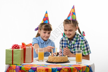 点蜡烛的孩子孩子们点蜡烛 蛋糕上配一个火柴 在生日派对的桌上背景