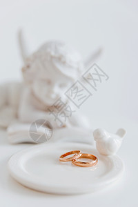 鲑鱼天使小号金色的婚戒配上白色的鸟和天使 爱情和婚姻的象征物 雕塑 戒指背景