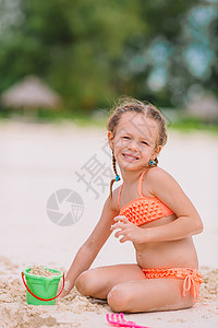 在热带度假期间玩沙滩玩具的可爱小女孩 热带假期 绿松石 水美丽的高清图片素材
