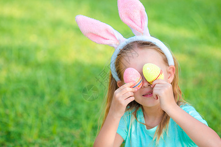 穿洋装兔子春日穿兔子耳朵和复活节鸡蛋的可爱小姑娘 快乐的背景