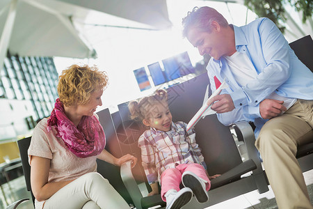 成年男子与可爱女儿在机场等候登机时玩飞机的画像图片