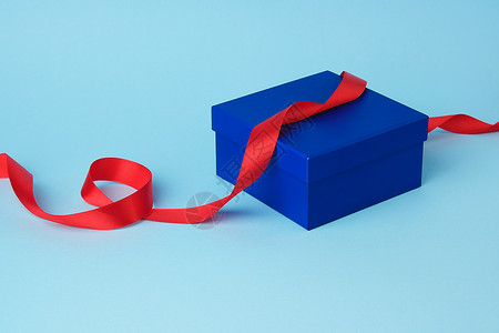 用于礼品和扭曲丝绸红丝带的普通蓝纸板盒 空的背景图片
