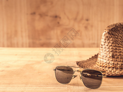 木制桌上的太阳镜和帽子 木制的 桌子 海滩 假期 时尚背景图片