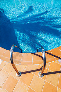 用楼梯游泳泳池 在蓝色游泳中抓条梯子 健康背景图片