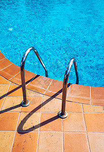 用楼梯游泳泳池 在蓝色游泳中抓条梯子 金属背景图片