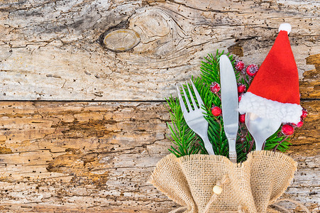 圣诞节或基督复临安息日晚宴餐桌位 配有餐具和红圣塔帽装饰品背景图片