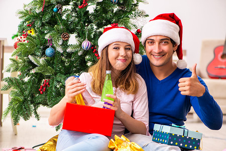 年青夫妇在家里庆祝圣诞日 庆典 拇指 开口背景图片