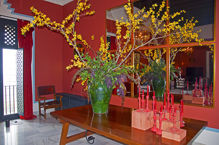 大绿花瓶 桌上有黄色花朵和红蜡烛 墙上有镜子 红内桌子高清图片素材