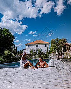 木甲板日光躺椅位于法国阿尔代什省的带木甲板和游泳池的法式度假屋 在法国南部度假屋的豪华假期中 一对夫妇在带木甲板的游泳池旁放松身心 克罗地亚背景