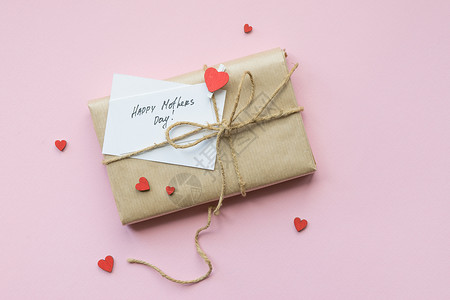 以棕色手工艺纸和领带绳包装在浅粉红色背景上 母亲节礼物盒 顶级风景 绳索 快乐的背景图片