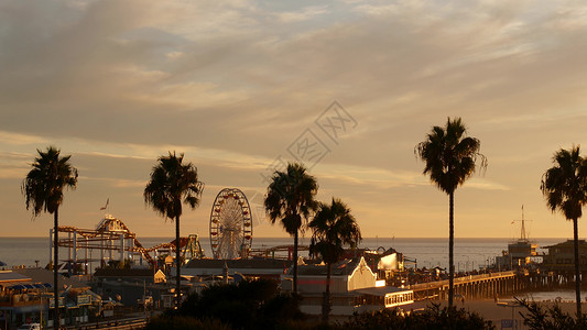 圣莫妮卡海滩经典的摩天轮 圣塔莫尼卡太平洋海滩度假村码头的游乐园 夏季加州美学 标志性景观 美国加利福尼亚州洛杉矶的象征 日落金色的天空和景背景