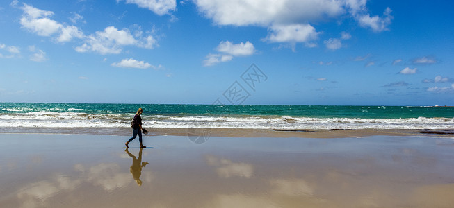 年轻女子在空旷的野生海滩上行走 在大大洋路的水面照着镜子美丽高清图片素材