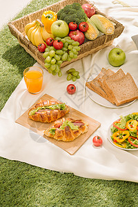 苹果篮户外夏季或春季野餐的健康食品和配饰 带新鲜水果的野餐柳条篮 面包和露营自然背景中的一杯清爽橙汁背景