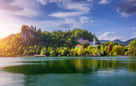 圣朱利安布莱德城堡和圣马丁教堂和布莱德镇令人惊叹的阳光明媚的景色 在湖中倒影 背景是朱利安阿尔卑斯山 布莱德湖 斯洛文尼亚 树 旅游背景