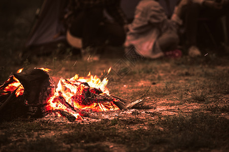 篝火帐篷在夏夜背景下 与游客一起点燃篝火 坐在森林露营帐篷附近明亮的篝火旁 一群学生在户外生火 旅行活动和长假周末 柴 男人背景