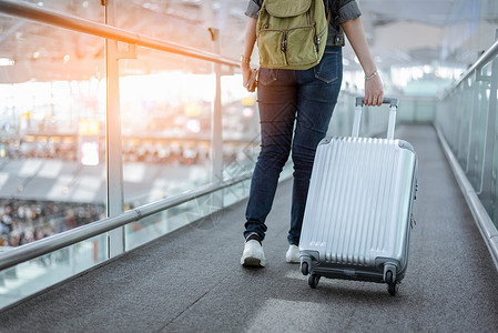 关闭女性旅行者的下半身 带着行李箱乘飞机去世界各地 机场航站楼自动扶梯上的女游客 白色的 步行背景