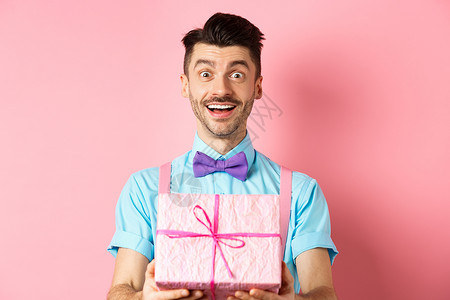 欢乐的祝生日快乐和赠予你礼物的人 包在盒子里 站在粉红背景上 穿着节日服装 Y 我 男性 派对背景图片