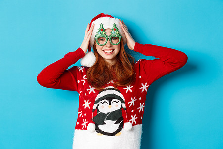 节日快乐和圣诞节的概念 有趣的红发少女庆祝新年 戴着圣诞帽和派对眼镜 站在蓝色背景下 成人 可爱的背景图片