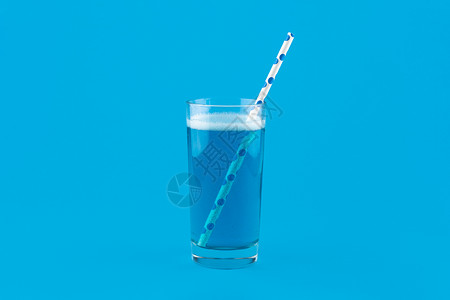 蓝色柠檬水 有气泡和鸡尾麦草 以蓝底隔离图片