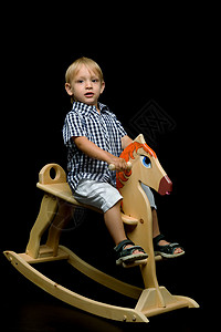 宝宝骑木马一个小男孩骑着木马 房间 幼儿园 童年 可爱的 玩具 幸福背景