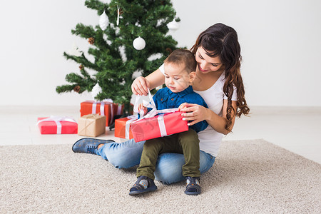 圣诞节 单身父母和假期概念 — 可爱的小男孩在家里为他的母亲拿着圣诞礼物 微笑孩子高清图片素材