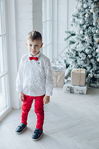 小caucasian男孩坐在 圣诞树附近 有礼物的圣诞树 庆典 乐趣展示高清图片素材