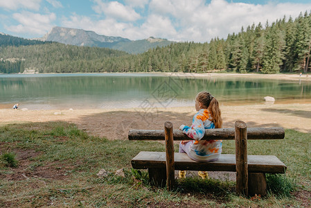 高山湖泊岸边的年轻女孩 山湖背景下的女孩背影 坐在黑山美丽的黑湖附近的年轻女孩 夏日清晨的原创壁纸 云 太阳春天高清图片素材