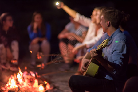 篝火音乐年轻朋友在营火周围放松 乐趣 成人 享受 微笑背景