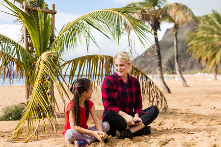 年轻妈妈和女儿 在海边海滩上 在海边关心高清图片素材