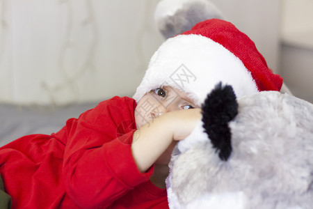 一个戴着圣诞老人帽子的可爱男孩的画像 滑稽的微笑的孩子 礼物 玩具 欢乐 庆典 魔法 冬天乐趣高清图片素材